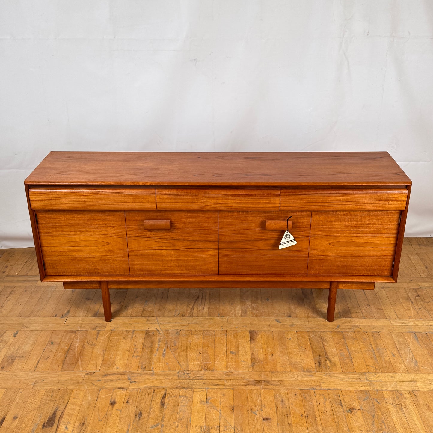 Wooden sideboard with drawers on a wooden floor against a white wall