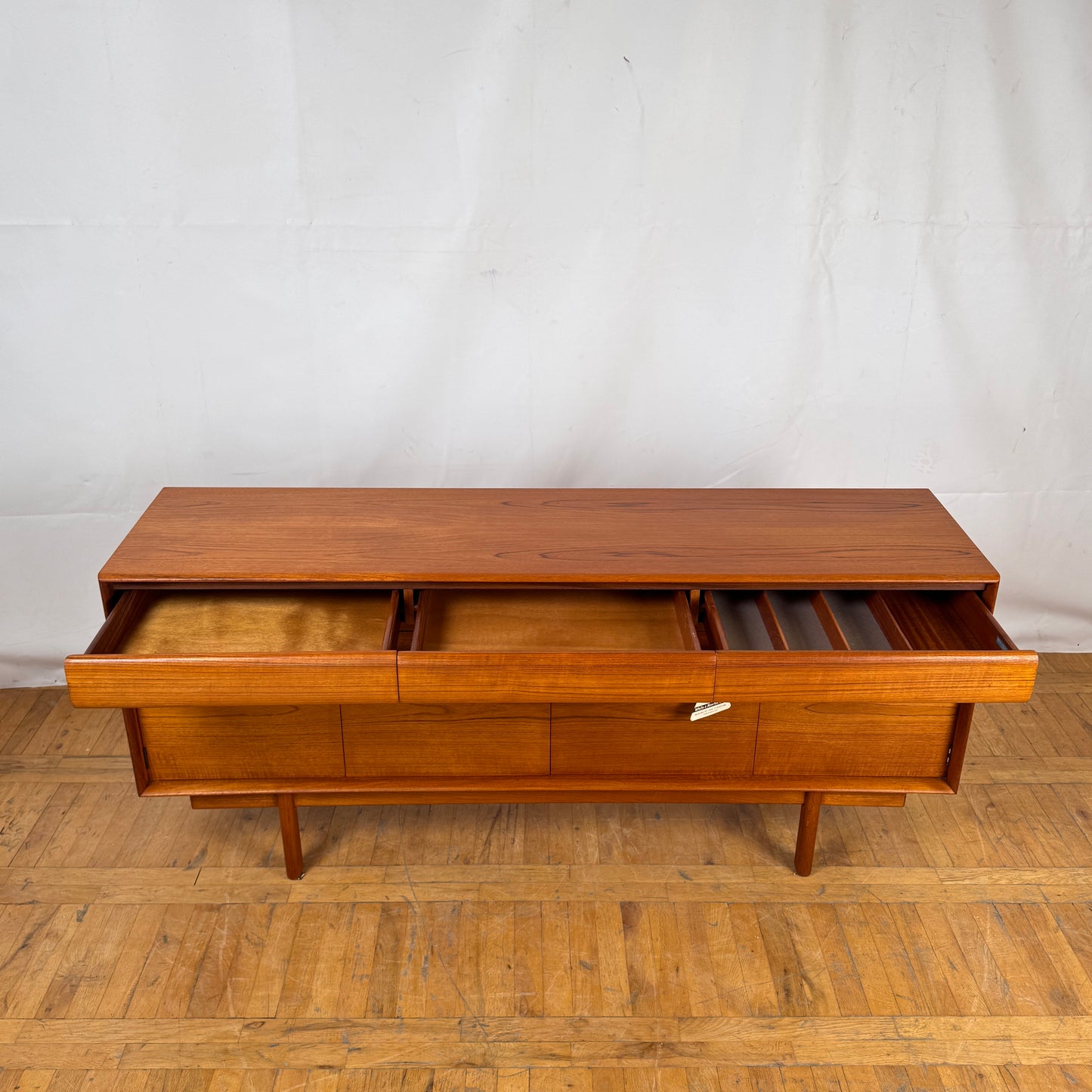Wooden desk with multiple drawers on a wooden floor against a white wall