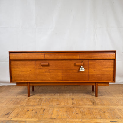Wooden dresser with multiple drawers on a wooden floor against a white wall