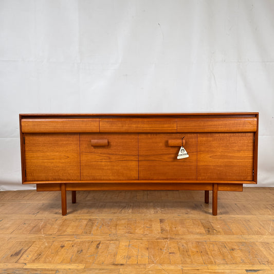 Wooden dresser with multiple drawers on a wooden floor against a white wall